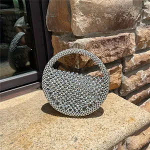 Detail of silver metallic beaded handmade evening bag with circular handle on stone