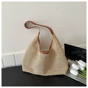 Detail of hand-woven beige straw hobo bag with brown leather trim and half-moon silhouette