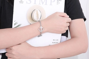 Close-up of a silver anchor bracelet with OT toggle clasp on a fashion magazine background
