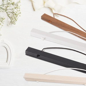 Detail of magnetic wooden poster hangers in four colors with hanging cords on wood background