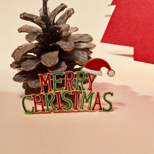 Golden Merry Christmas brooch with red and green enamel and festive pine cone decor