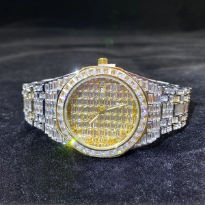 Detail of gold luxury watch with square diamond pave setting and date display at three