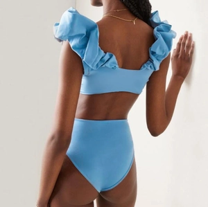 Detail of light blue bikini featuring dramatic ruffle shoulders and high waisted cut