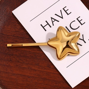 Detail of 18K gold-plated star hair clip on wooden background with aesthetic card