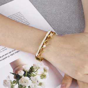 Gold infinity bracelet with white crystals and shell inlay on a model's wrist