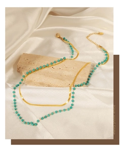 Close-up of golden double-layer necklace with turquoise beads on elegant stone base