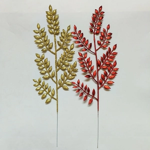 Dettaglio di foglie artificiali glitterate oro e rosse per decorazioni natalizie