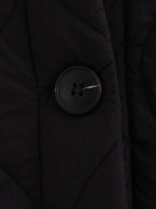 Detail of a dark brown four-hole button on black quilted cotton coat fabric texture