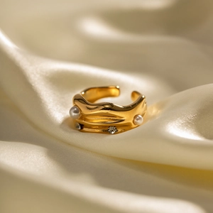 Detailed view of 18k gold plated C-shape ring with pearls and crystals on silk fabric