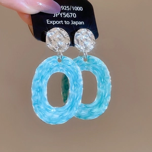 Macro shot of 925 silver stud earrings with blue marbled oval hollow pendants
