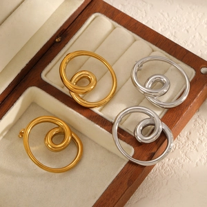 Two pairs of gold and silver knot earrings displayed in a premium wooden jewelry box