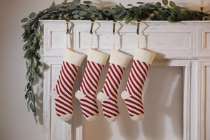 Detail of four red and white striped knitted Christmas stockings hanging on a white fireplace
