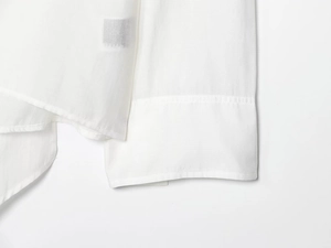 Close-up of high-quality white cotton fabric stitching on sleeve cuff and hem of blouse
