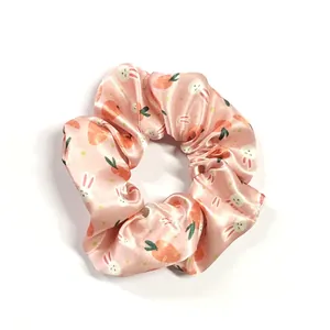 Detailed view of pink satin scrunchie with cute Easter bunny and carrot prints