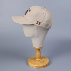 Détail d'une casquette beige structurée avec broderie 3D marron sur un modèle de tête