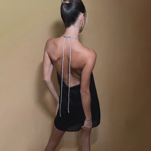 Détail d'une robe courte noire dos nu avec des bretelles en strass argentés brillants