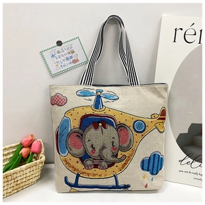 Detail of cute elephant embroidery on cream canvas tote with striped handles