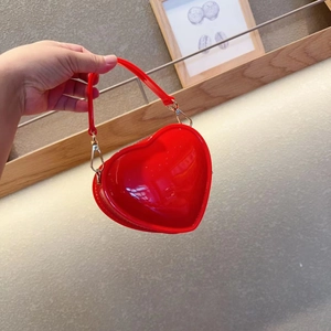 Detail of red heart-shaped jelly bag featuring a glossy finish and gold chain strap