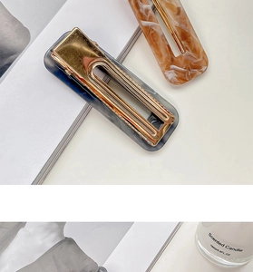Detail of acrylic marble pattern hair clips with gold metal base on a white desk