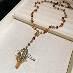 Detailed macro shot of vintage amber beaded necklace with large teardrop crystal pendant