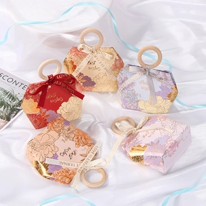 Detail of hexagon wedding favor boxes with gold floral patterns and wooden ring handles
