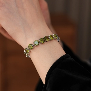 Close-up of olive green zircon tennis bracelet on wrist with elegant silver-plated finish