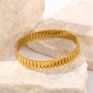 Detailed close-up of 18K gold-plated stainless steel oval bangle with vertical striped texture