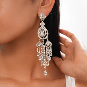 Close-up of sparkling rhinestone flower tassel earrings worn by a model in silver finish