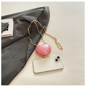 Mini pink heart-shaped bag with gold chain strap shown next to a smartphone for scale