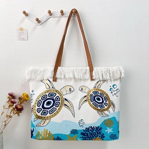 Detail of white canvas tote bag with brown leather handle and elegant fringe tassel accents