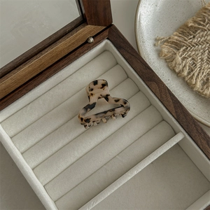 Close-up of leopard pattern acetate hair claw clip inside a beige velvet jewelry box