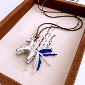 Silver pony necklace with blue beaded tail and brown braided cord on a vintage tray