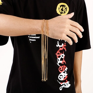 Close-up of multiple golden stainless steel curb chains on male model arm