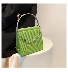 Detail of lime green textured handbag with silver circular handle and metal ball clasp