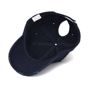 Detail of navy cotton ponytail hat showing the worn brim and inner stitching