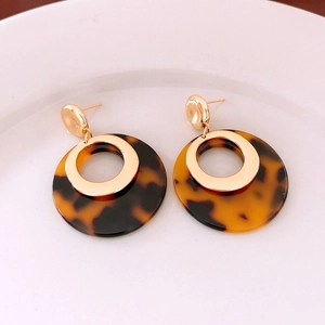 Detail of 18K gold plated hoop earrings with tortoise shell resin pendants on white ceramic