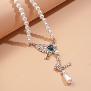 Detail of luxury pearl necklace with crystal bird pendant and colorful gemstones