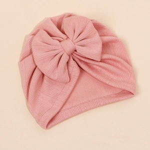 Détail du bonnet turban rose pour bébé en maille avec un grand nœud et tissu texturé