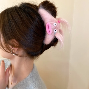 Side view of cute pink fuzzy monster hair claw clip worn on model hair accessory