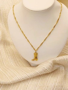 Detailed close-up of a vintage golden cowboy boot pendant with engraved patterns on a rope chain