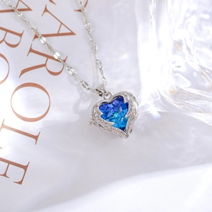 Close-up of heart-shaped blue zircon necklace with silver wings and halo diamond pavé