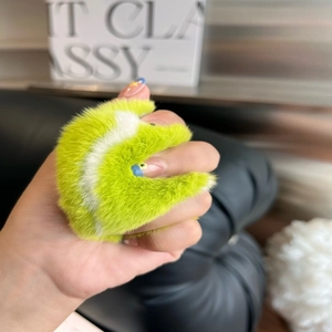 Neon green faux rabbit fur tennis ball keychain held by a model for fashion accessory