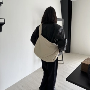 Rear view of a beige padded puffer tote bag showing soft sponge texture and wide strap