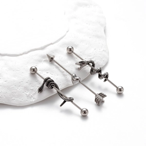 Stainless steel industrial barbells featuring snake and heart arrow designs on stone