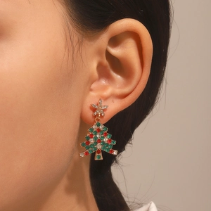 Close-up of a festive Christmas tree earring featuring colorful rhinestones on a gold base