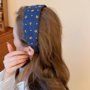 Détail du serre-tête en tissu bleu marine avec étoiles dorées pour effet volume de tête