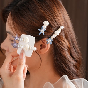 Détail des barrettes étoiles de mer et coquillages avec cristaux portées par modèle
