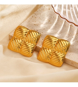 Close-up of golden square stud earrings featuring textured geometric ripple patterns
