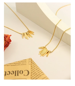 Detail of gold-plated tassel necklace with geometric rectangular bars and snake chain