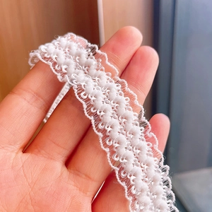 Close-up of soft white pom-pom lace trim detailing for baby headbands and diy sewing